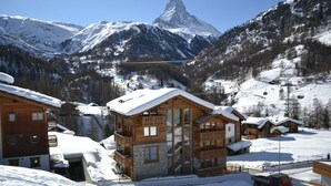 A wooden chalet with a large glass window, surrounded by snow-covered mountains and a clear sky. - Hotel Mountain Paradise (Zermatt)