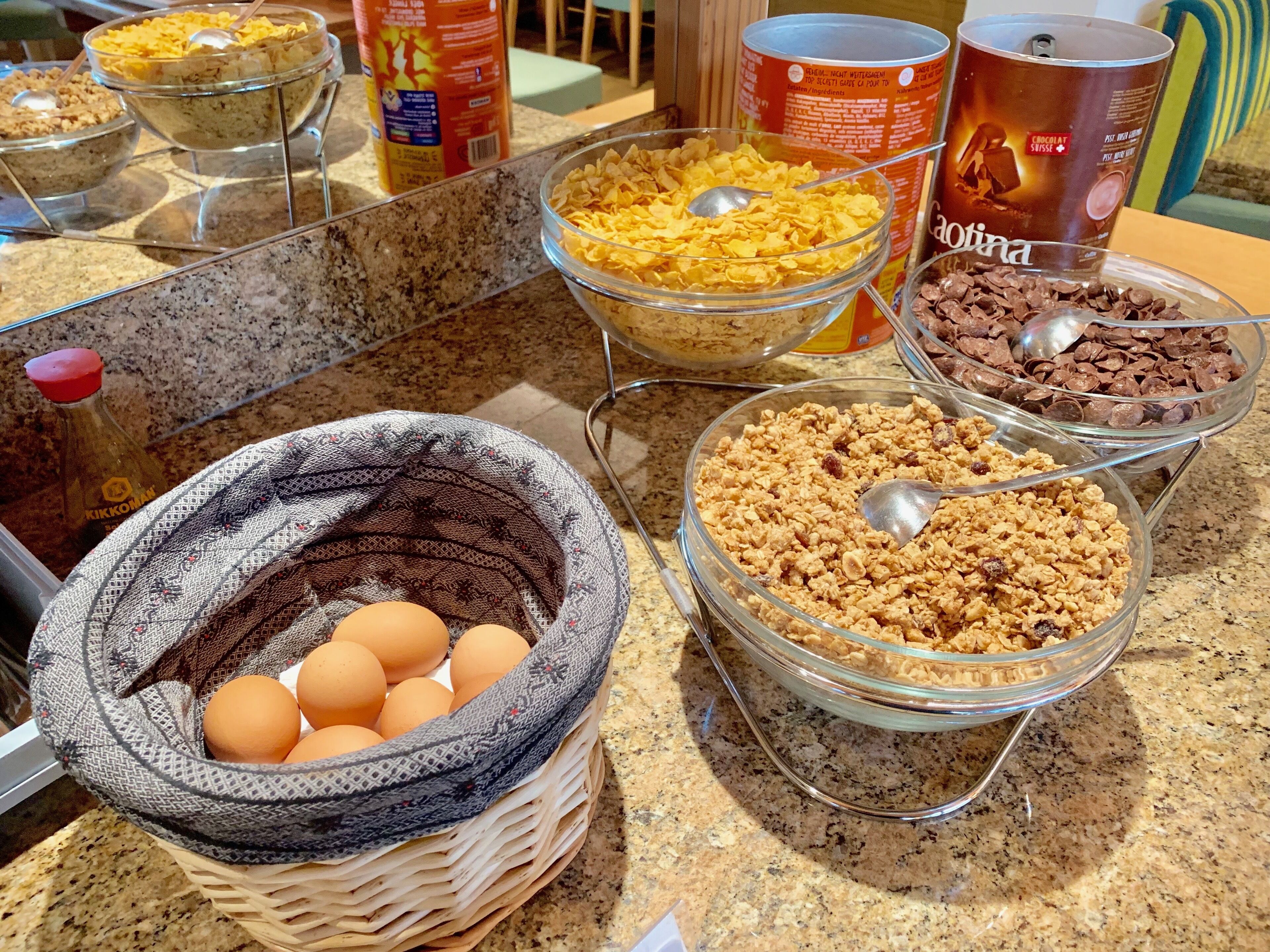 A buffet with various food items including cereal, chocolate chips, and eggs.