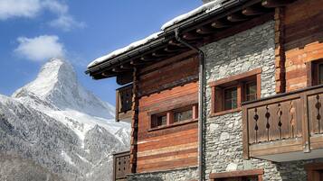 Experience the rustic charm of this mountain lodge, offering breathtaking views of the surrounding landscape and a prominent mountain peak.