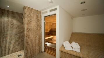 Una spa con sauna in legno, pareti in piastrelle e una panca con asciugamani.