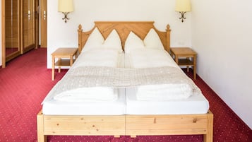 Una cama doble con estructura de madera, dos mesitas de noche y lámparas fijadas a la pared.