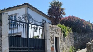 Un edificio de piedra con una verja metálica, un camino adoquinado y una palmera.