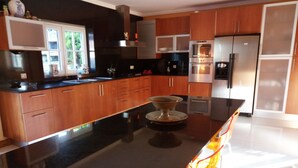 Una cocina moderna con armarios de madera, encimera negra y electrodomésticos de acero inoxidable.