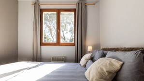A bedroom with a bed, a nightstand, a lamp, and a window with curtains.