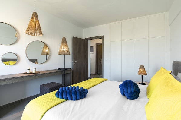 A modern bedroom with a large bed, bedside lamps, and a mirror on the wall.