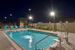 Una piscina con una escalera de metal y sillas de descanso.