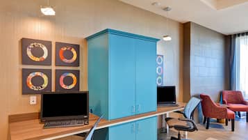 A modern office space with teal cabinets, two desks with computers, and office chairs.