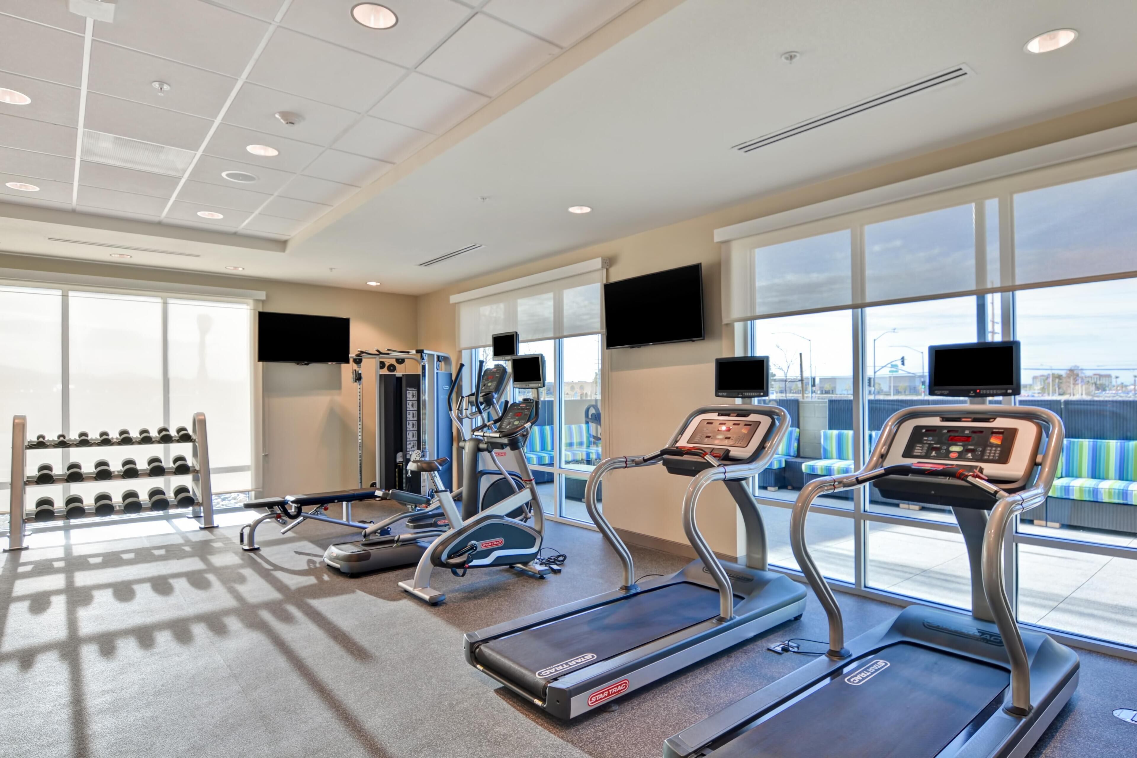 A gym with treadmills, weight machines, and dumbbells.