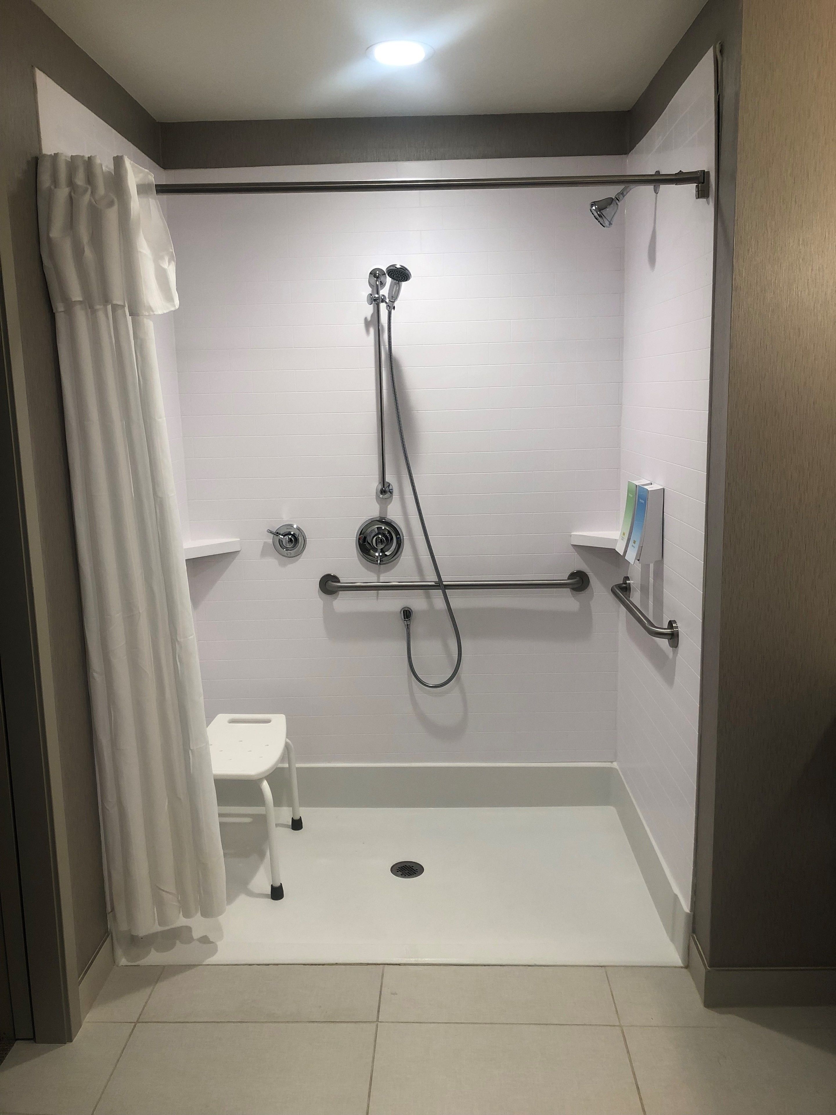 Un baño moderno con cabina de ducha, un lavabo pequeño blanco y un inodoro.