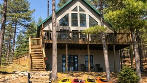Une cabane avec un balcon, un escalier et des kayaks.