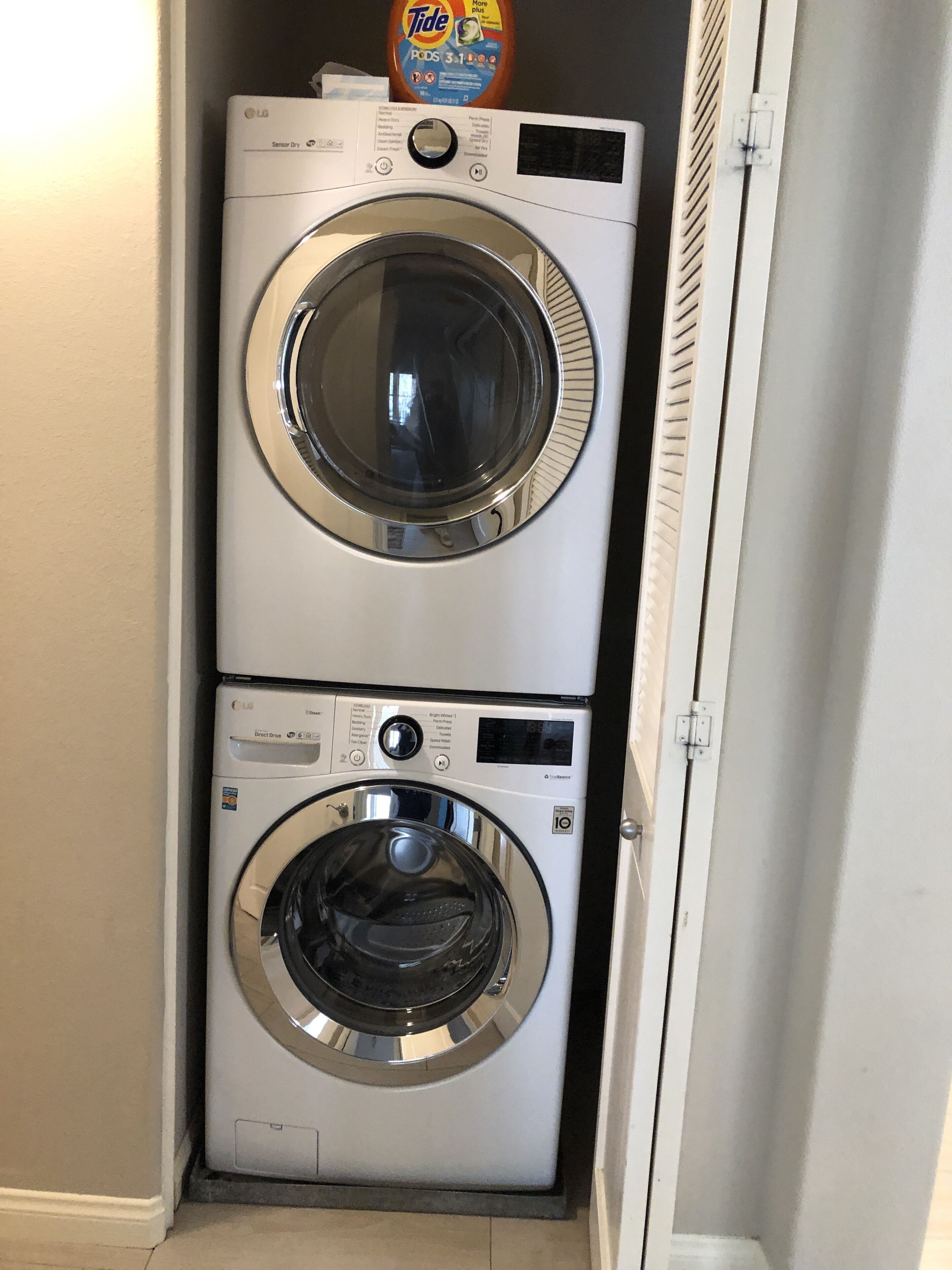 Une machine à laver et un sèche-linge superposés, avec une bouteille de lessive Tide posée sur le dessus.