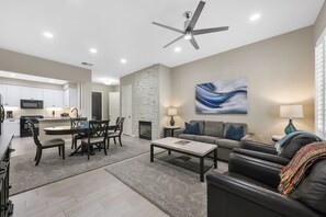 A modern living room with a dining area, kitchen, and fireplace.