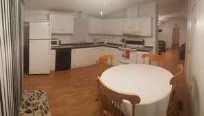 Una cocina con armarios blancos, microondas, lavavajillas y una mesa de comedor con cuatro sillas.
