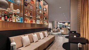 Eine moderne Hotelhalle mit einer Couch, einem Glastisch und einer Bar mit verschiedenen Flaschen.