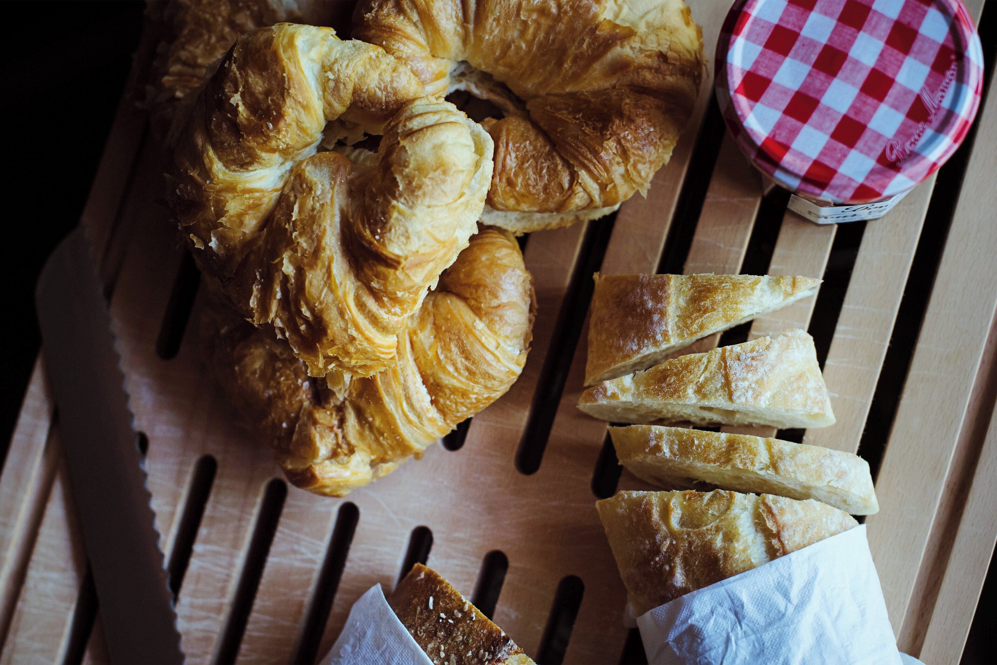A wooden table with pastries and a jar of jam.