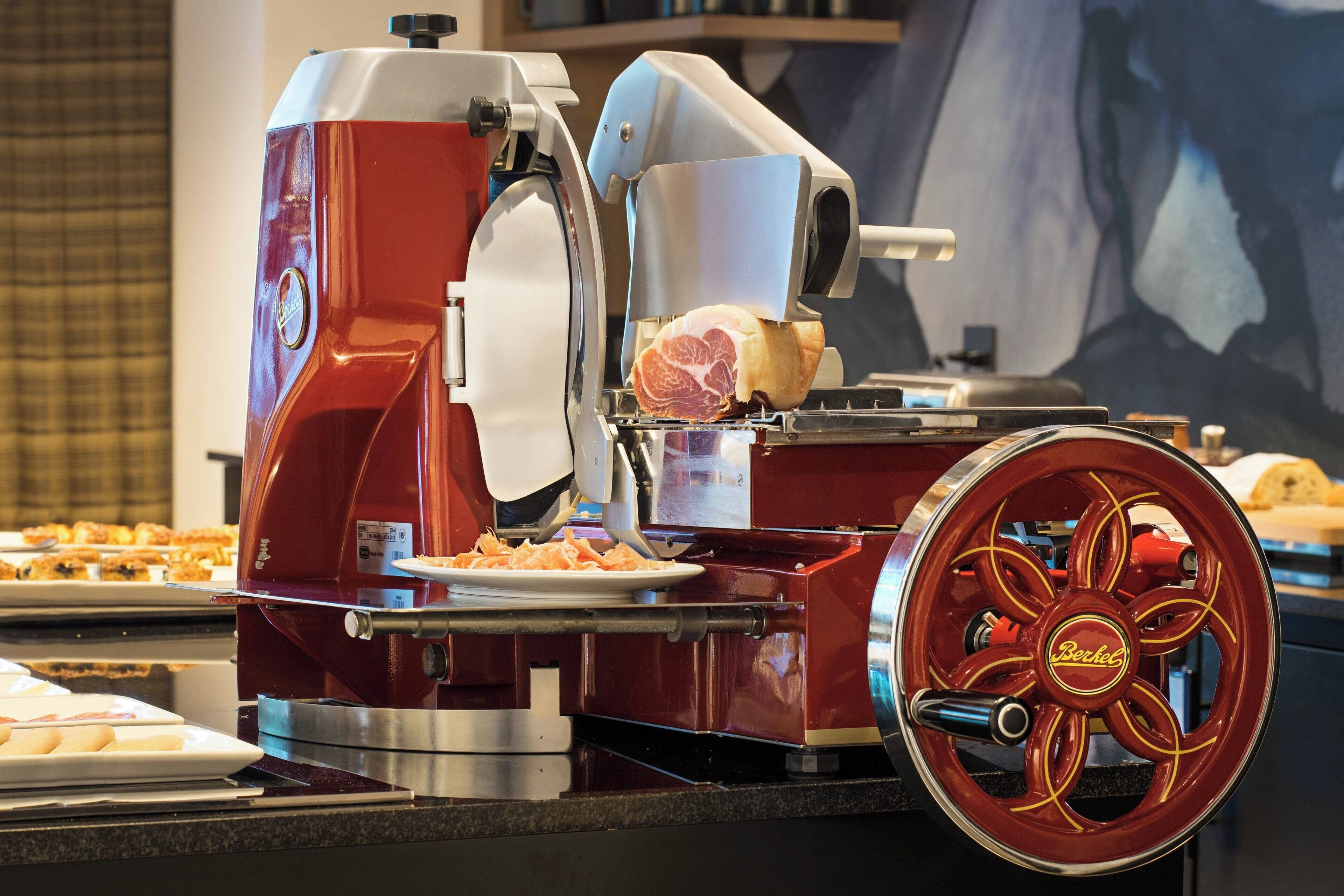 A red and white food preparation machine with a large wheel and a plate of food on its counter.