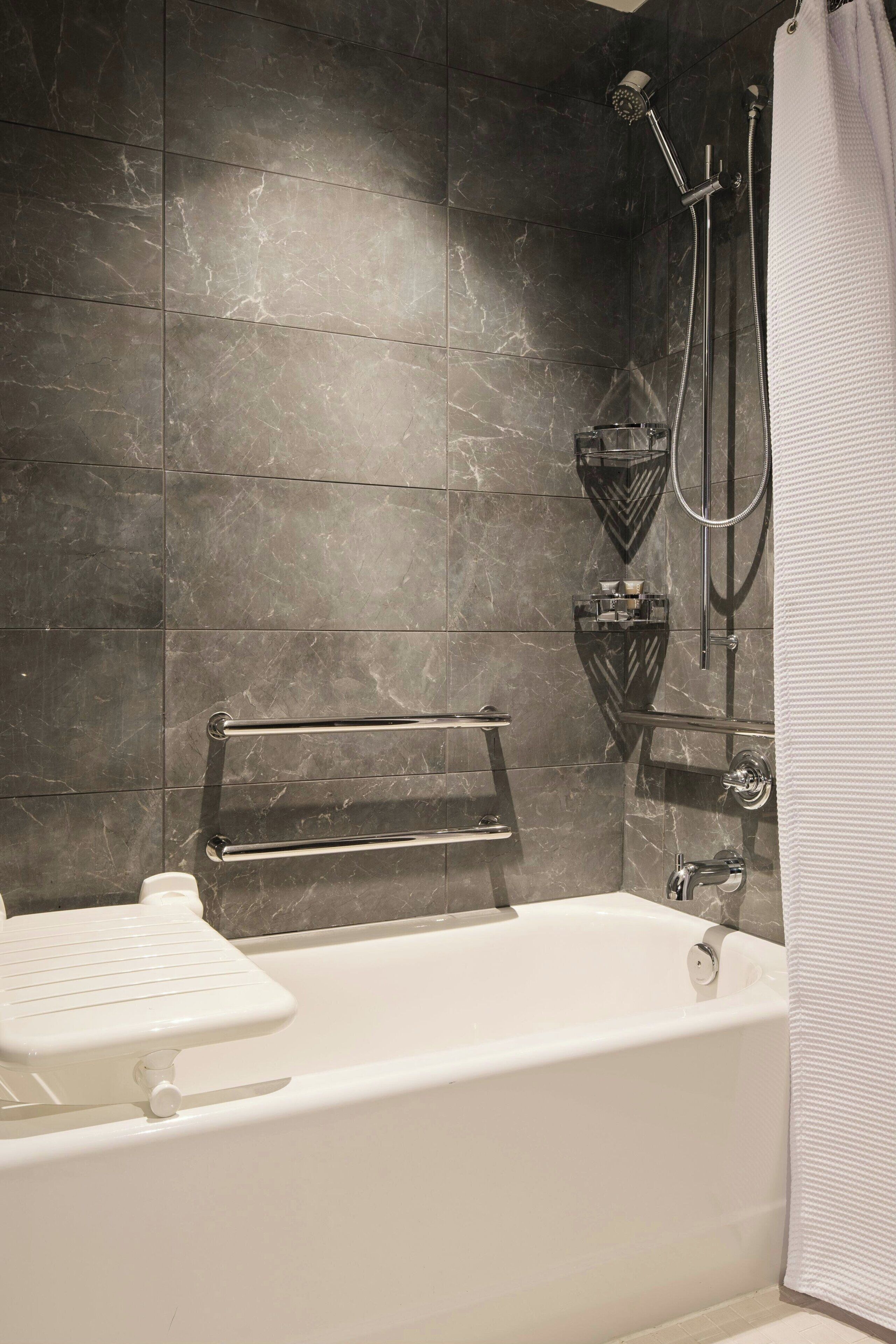 Ein modernes Badezimmer mit einer Badewanne, einer Dusche inklusive Handbrause und einem Handtuchhalter.