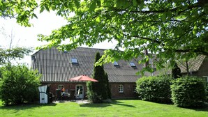 A house with a sloped roof, a brick exterior, and a well-maintained lawn. - Spacious vacation residence for 6 pers. with pool and garden. Sauna - shared use (Stadland-Reitland)