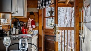 Una cocina acogedora de estilo cabaña con paredes de madera, encimera de mármol y zona de comedor con una mesa preparada para dos.