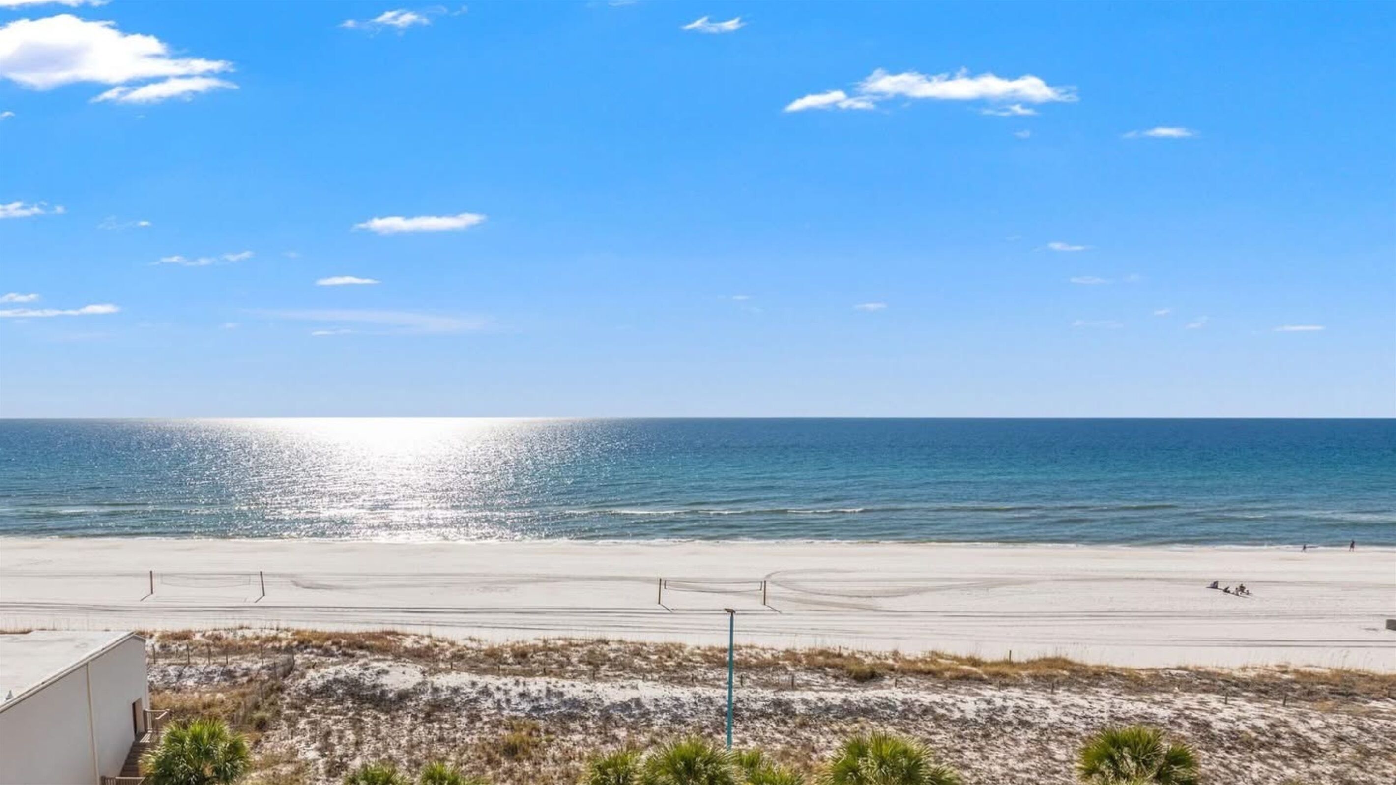 A beach with a clear sky, a sandy shore, and a few people in the distance.