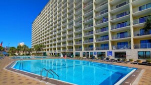 A hotel with a large pool, multiple balconies, and a tiled walkway. - Gulf-Front Comfort, Personally Prepared for You (Panama City Beach)