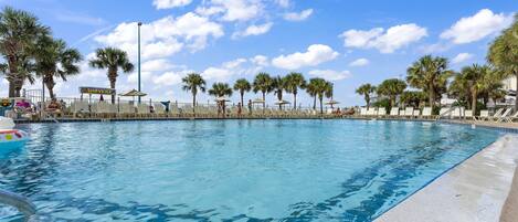 A swimming pool with lounge chairs and palm trees.