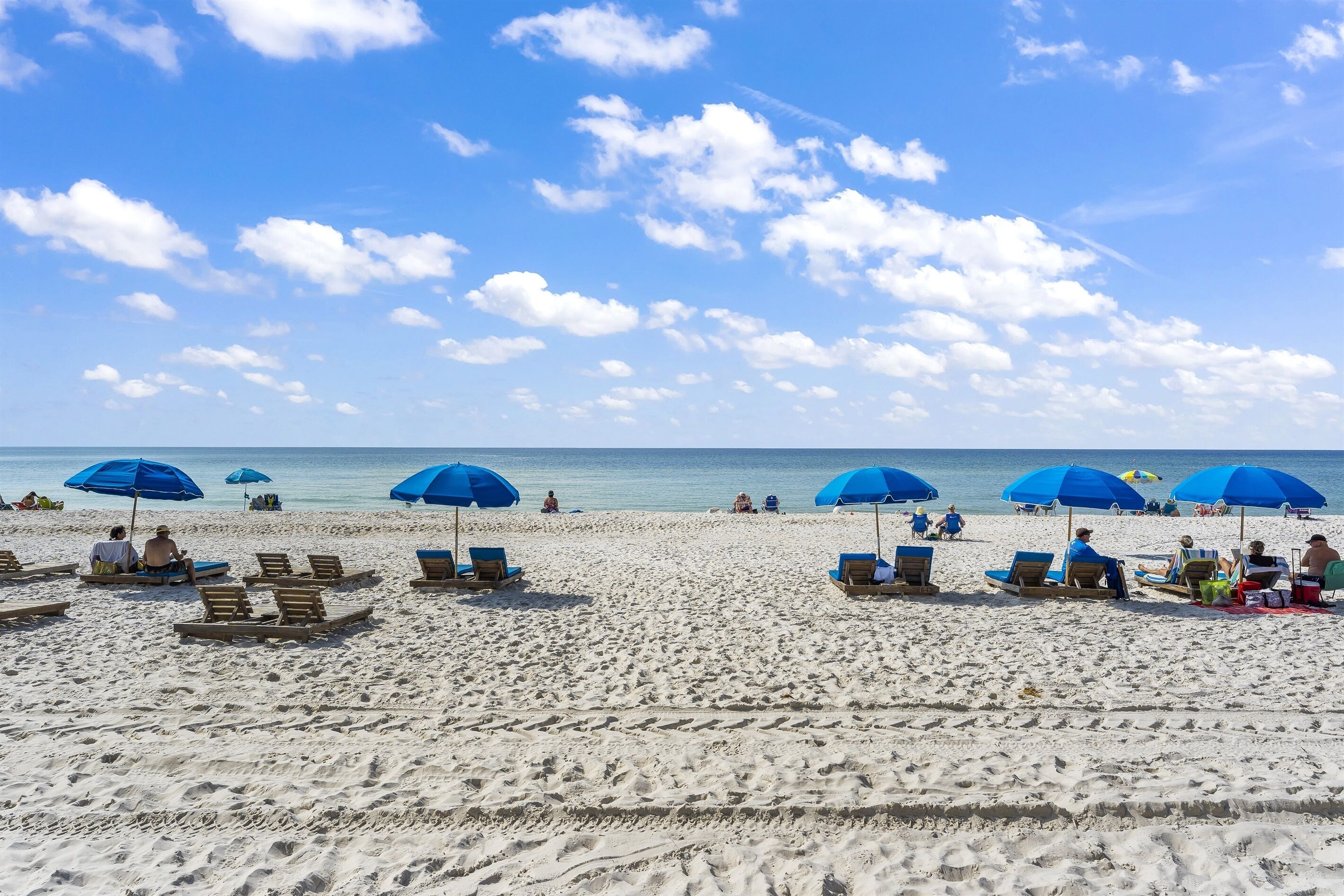 Una spiaggia con lettini e ombrelloni, un cielo sereno e l'oceano sullo sfondo.