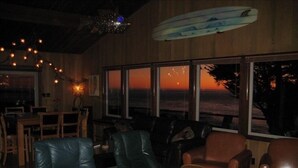 A room with leather chairs, a dining table, and large windows with a sunset view. - Pelican Point, Dramatic Ocean & Coast Views, Spa, Next to Town (Mendocino)