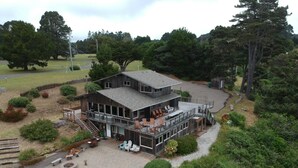 A two-story building with a deck, outdoor seating, and a fire pit. - Pelican Point, Dramatic Ocean & Coast Views, Spa, Next to Town (Mendocino)