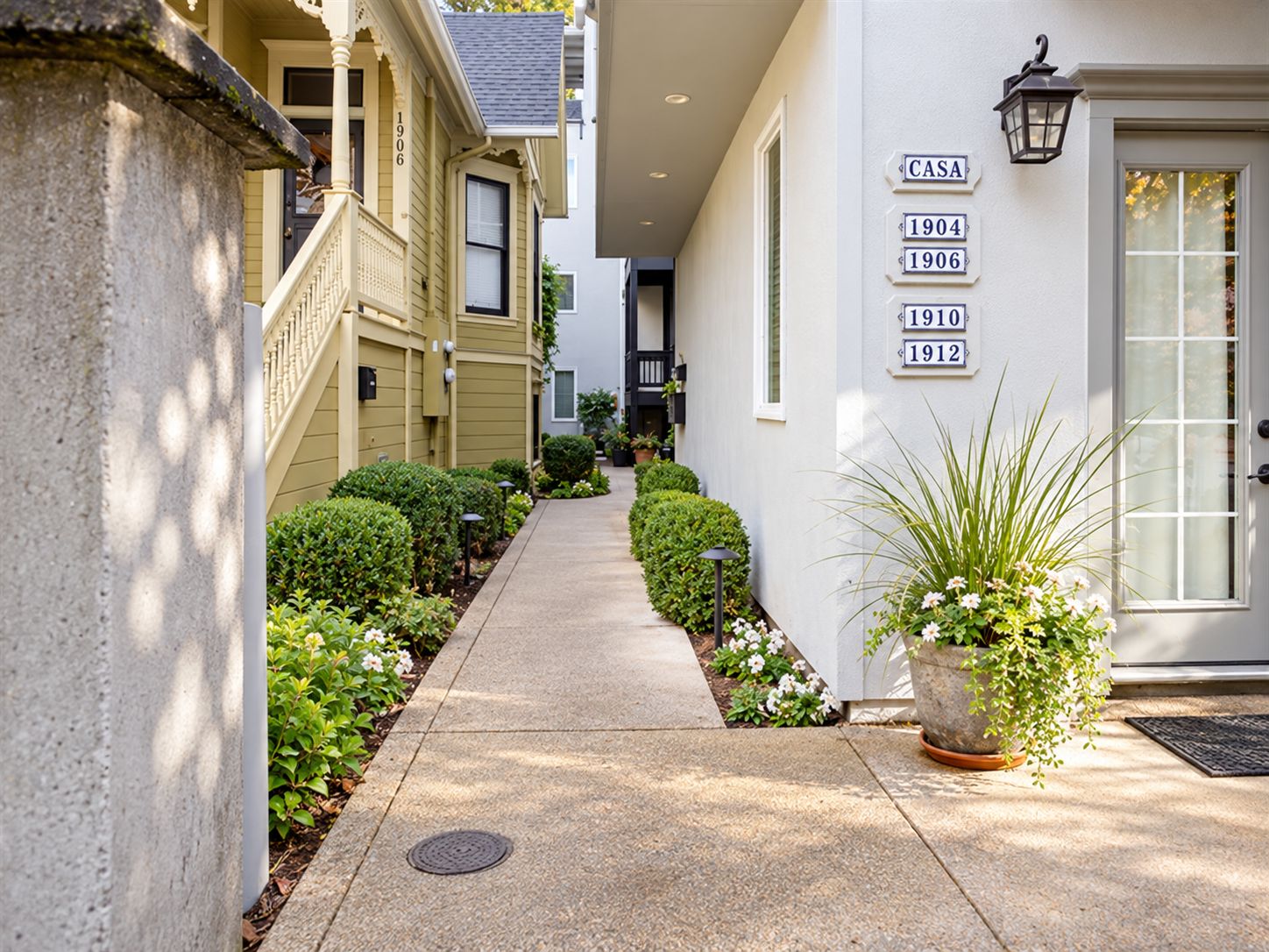 A narrow pathway leading to a building with numbered doors, suggesting a residential or hotel setting.