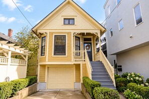 A two-story house with a front porch, a garage, and a staircase leading to the entrance.