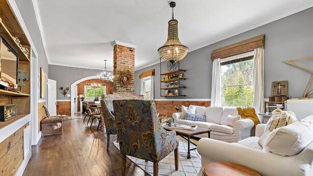 A spacious living room with a fireplace, a dining area, and a large window providing natural light.