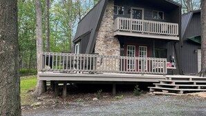 A two-story cabin with a stone facade, a balcony, and a deck.