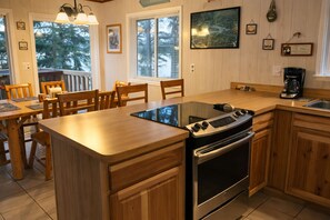 A kitchen with wooden cabinets, a built-in oven, a coffee maker, and a dining area with wooden chairs and a table.