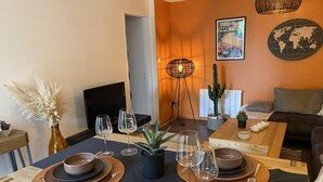 Zona pranzo con un tavolo apparecchiato per due, una televisione sullo sfondo e una mappa del mondo appesa al muro.