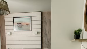 Camera da letto con un letto, comodini, una scrivania, una sedia, un cesto appeso e uno scaffale a parete.