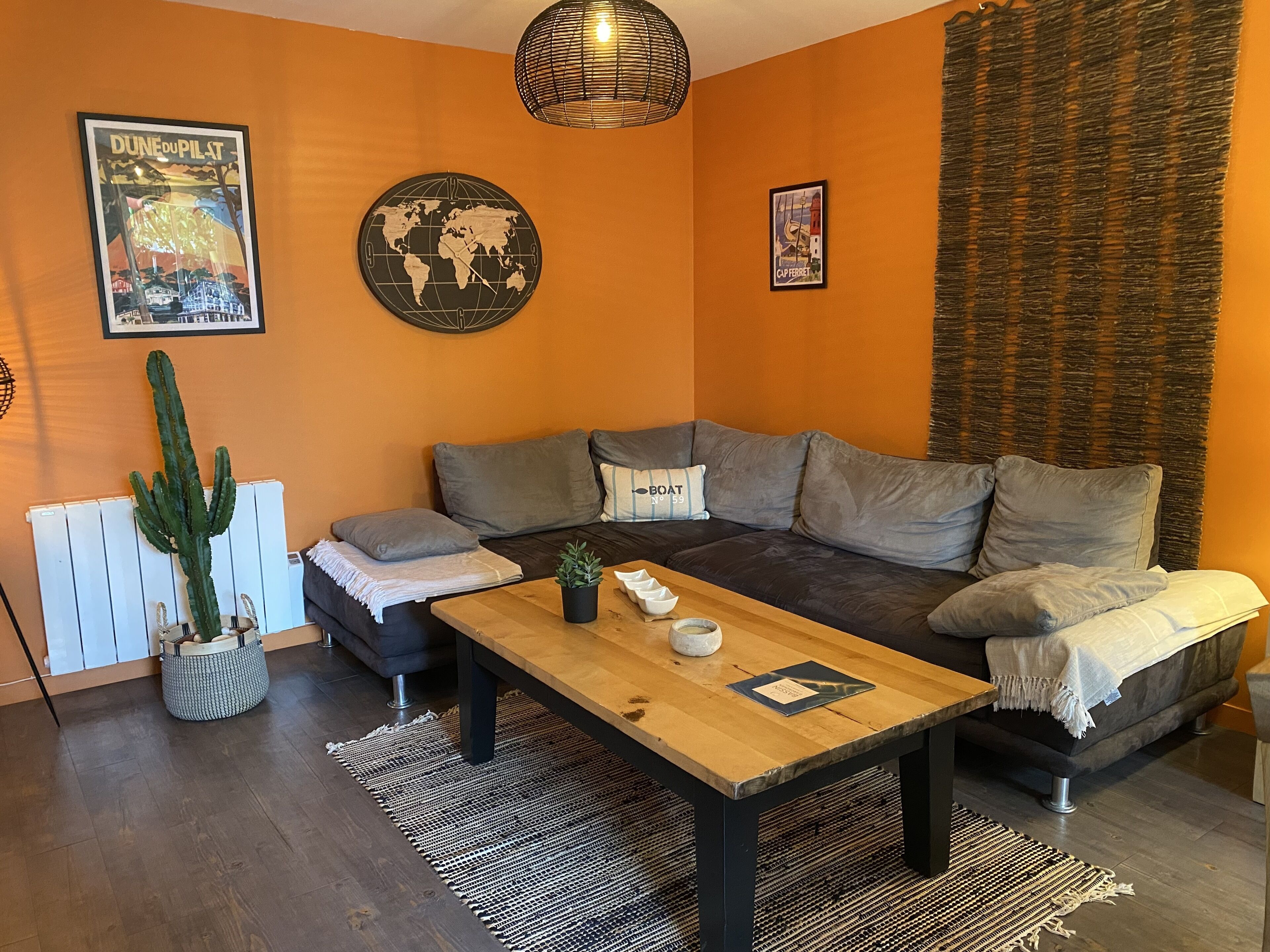 A cozy living room with a dark gray sofa, a wooden coffee table, and a world map clock.
