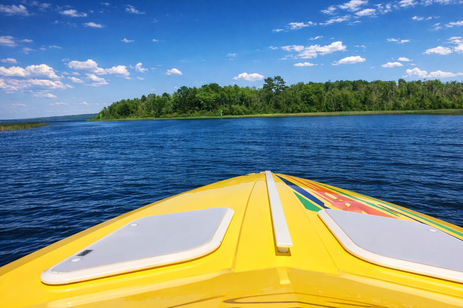 A yellow kayak on a calm lake with a forested island in the background.