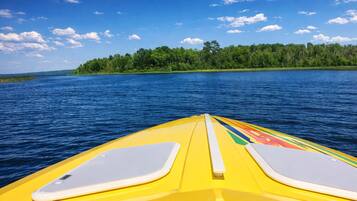 A yellow kayak on a calm lake with a forested island in the background.