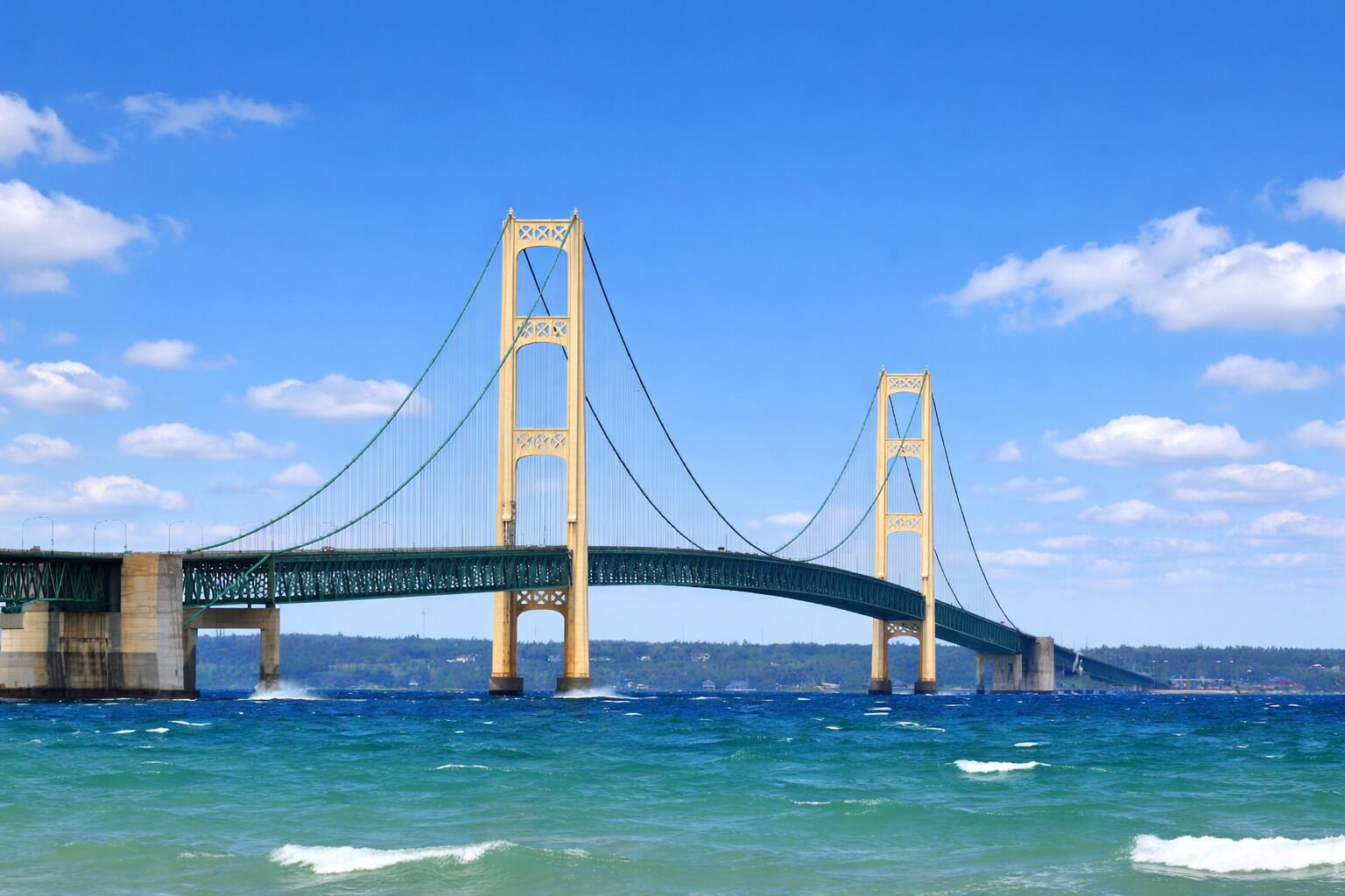 Un grand pont suspendu enjambant une étendue d’eau, avec deux pylônes et une travée centrale.