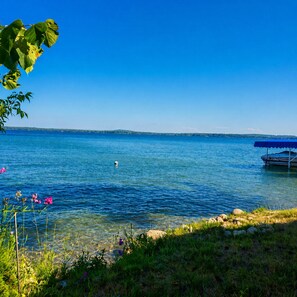 Ein ruhiger See mit blauem Himmel, einer Anlegestelle mit blauer Markise und dichter Ufervegetation.