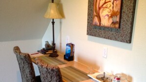 Un comedor con una mesa, sillas, una lámpara y un cuadro en la pared.