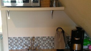 Una cocina equipada con microondas, cafetera y pileta.