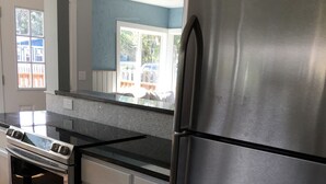 A kitchen with stainless steel appliances, white cabinets, and a window with a view of a fence and trees. - BRIGHT! 1.5 Blocks to Beach - Light Filled House (3 Bedroom Plus Den)  (Seaside)