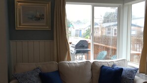 A beige sofa with patterned cushions, a framed picture on the wall, and a view of a backyard through a window. - BRIGHT! 1.5 Blocks to Beach - Light Filled House (3 Bedroom Plus Den)  (Seaside)