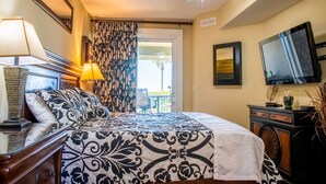 Una camera d'albergo con un letto, una ventola a soffitto, una televisione e un balcone con vista.