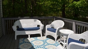 Un espace extérieur aménagé, abrité et doté de meubles en osier et d’un tapis à motifs.
