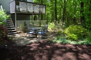 Eine Terrasse mit Tisch und Stühlen, umgeben von einem Holzzaun und einem Garten.