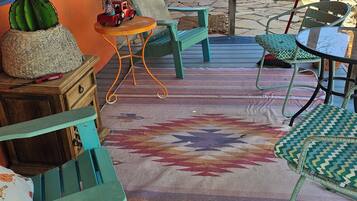 Un patio con mobiliario exterior, un tapete estampado y una decoración de cactus.