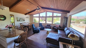 A spacious living area with a high ceiling, wooden beams, and large windows offering a view of the outdoors. - BEST VIEWS! Sleeps 8 Balcony, Firepit, Lawn, Patio, Wildlife (Sedona)